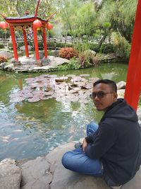 Portrait of young man sitting by lake