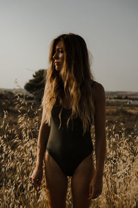 Beautiful woman standing on field against clear sky