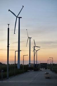 Wind turbines on field against sky during sunset