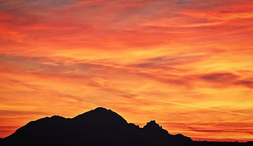 Silhouette mountains against dramatic sky during sunset