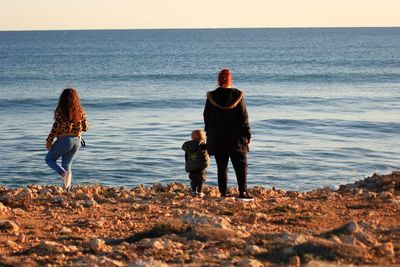 Rear view of women and child standing at beach