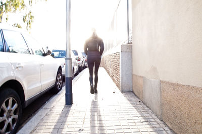 Rear view of woman walking on footpath in city