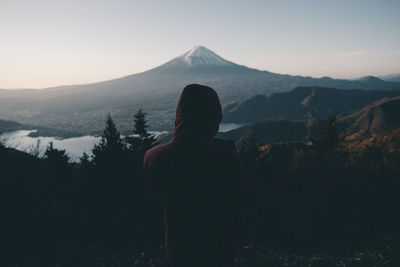 Rear view of man standing on mountain against sky