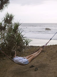 Woman relaxing on hammock at ocean coastline