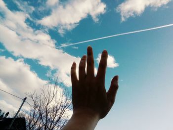 Low angle view of human hand against sky