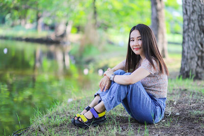 Beautiful young woman sitting on land