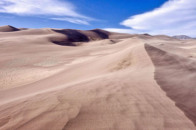 Scenic view of desert against cloudy sky