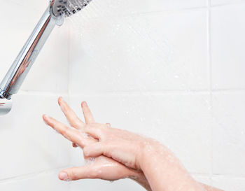 Woman washing hands with soap in shower.