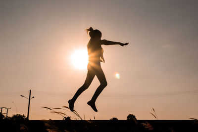 Low angle view of silhouette man jumping against sky during sunset