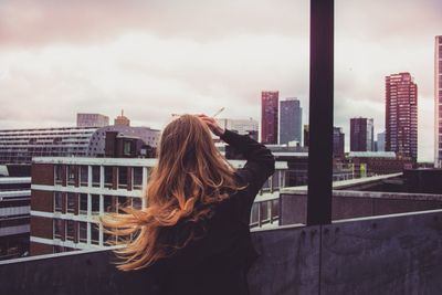 Rear view of woman in city against sky