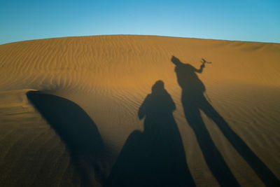 Shadow of people on sand dune