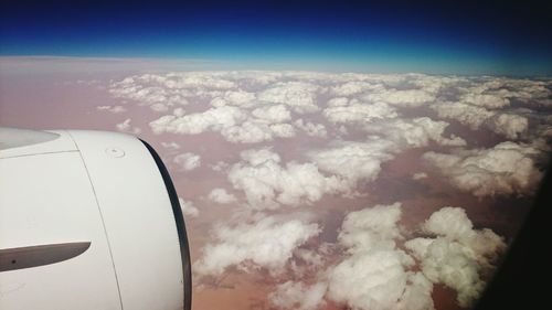 Close-up of airplane flying over landscape against sky