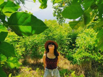 Portrait of young woman standing against trees