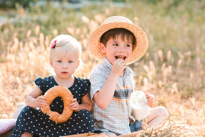 Cute brother and sister sitting on picnic blanket in park