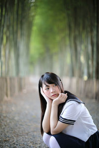 Side view of young woman crouching in bamboo groove