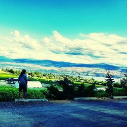 Rear view of woman standing on landscape against sky