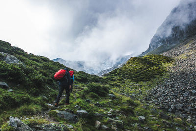 Rear view of man standing on mountain against sky