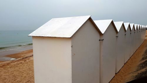 Beach cabins against white sky