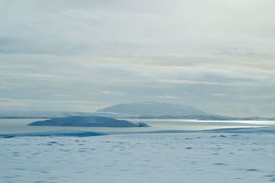 Scenic view of sea and snowcapped mountains against sky