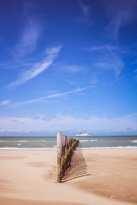 Wooden posts on beach against sky