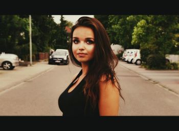 Portrait of young woman on road in city