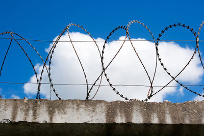 Low angle view of barbed wire against blue sky