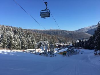 Ski lift over snowcapped mountains against sky