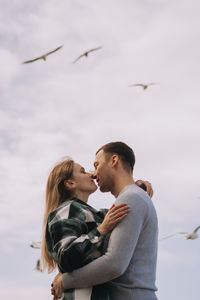 Couple kissing against sky