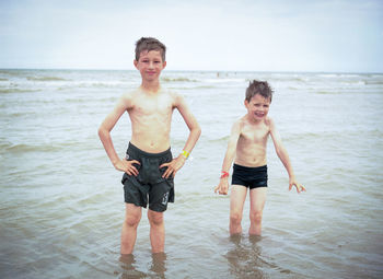 Full length of happy boy standing on beach against sky