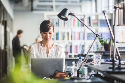 Creative businesswoman using laptop at desk in office