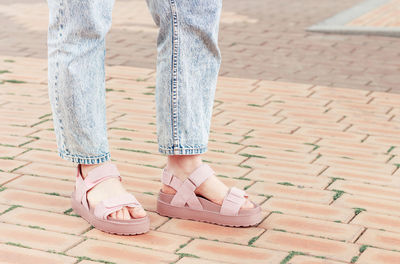 Female feet in a pink sandals on concrete background close-up.