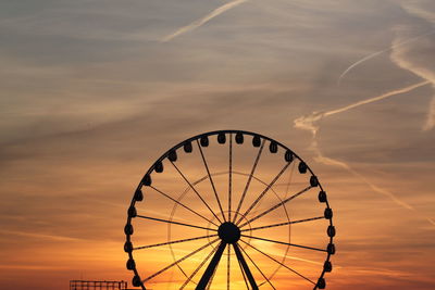 Low angle view of ferris wheel against sky during sunset