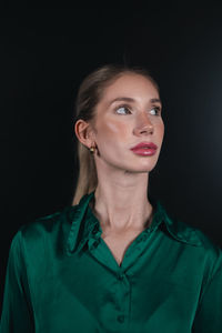 Portrait of young woman against black background