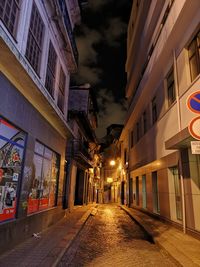 Empty road along buildings at night