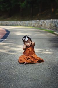 Portrait of cute girl sitting on road