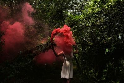 Woman holding distress flare while standing by trees