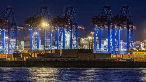 Low angle view of cranes at harbor