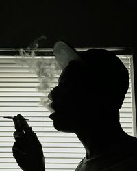 Close-up of silhouette man holding cigarette at night