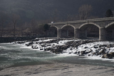 Arch bridge over river during winter