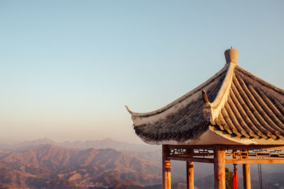 Panoramic view of roof and mountains against clear sky