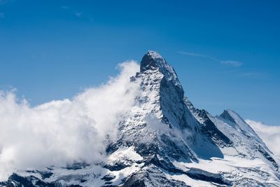 Scenic view of snowcapped mountains against blue sky