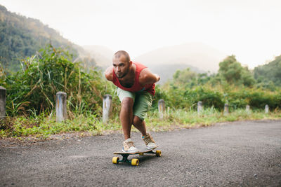 Man skateboarding on road against mountain