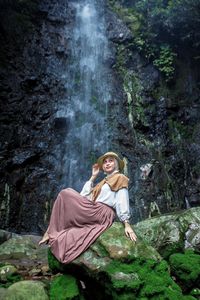 Travel woman sitting on rock enjoying waterfall nature