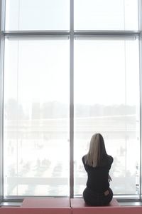 Rear view of woman looking through window