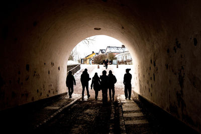 Silhouette people walking in tunnel