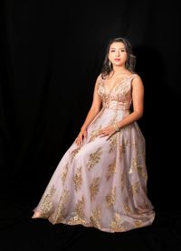 Portrait of woman sitting against black background