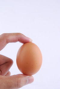 Close-up of hand holding apple against white background