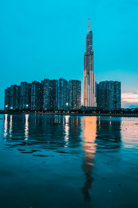 Sea by modern buildings against blue sky