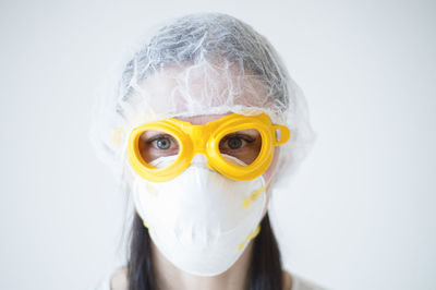 Close-up portrait of woman wearing mask and goggles against white background