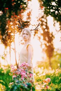 Low angle view of woman standing by flowering plants in park